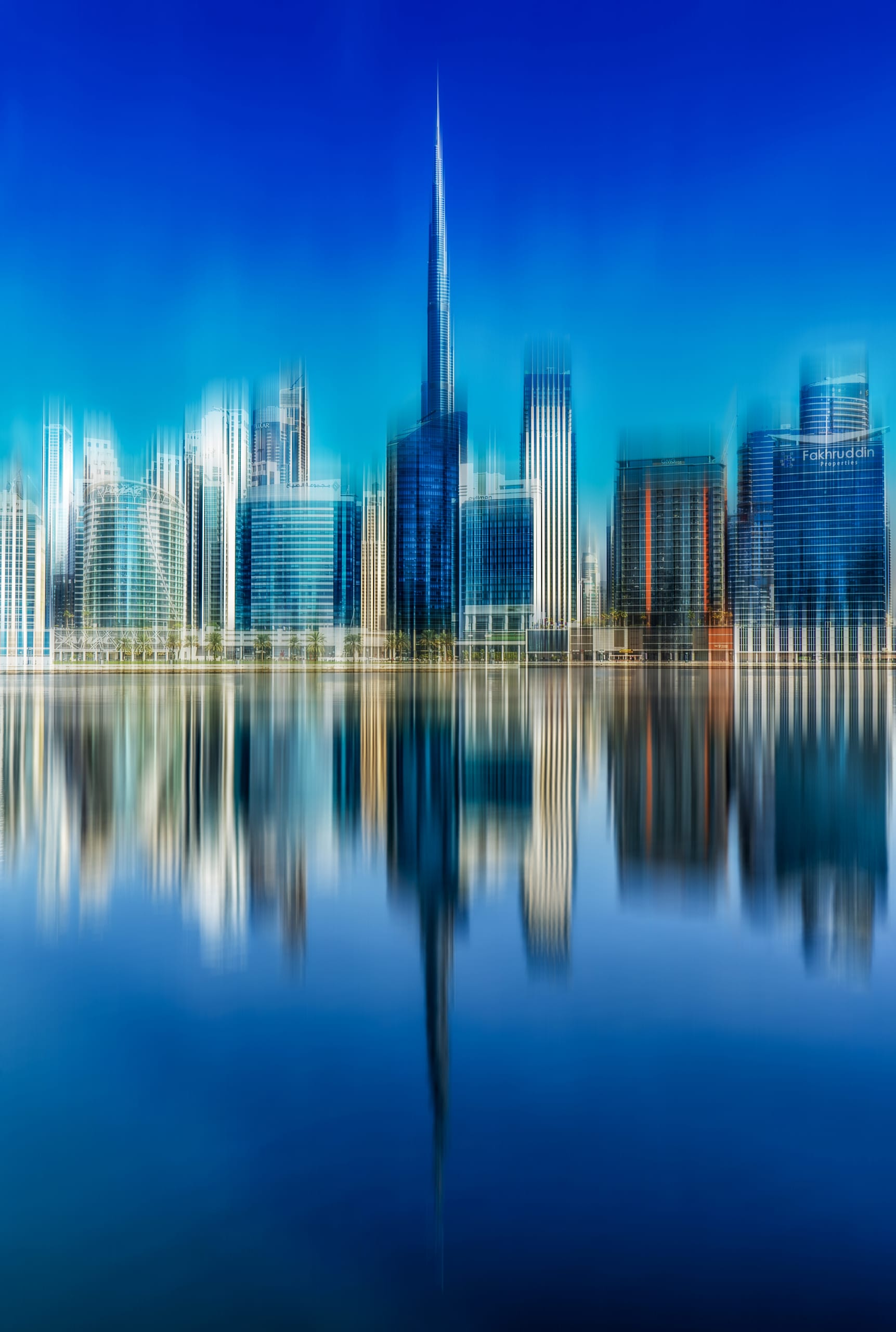 Architectural skyline reflection on water with vertical motion blur creating vertical streaks of blue and white tones.