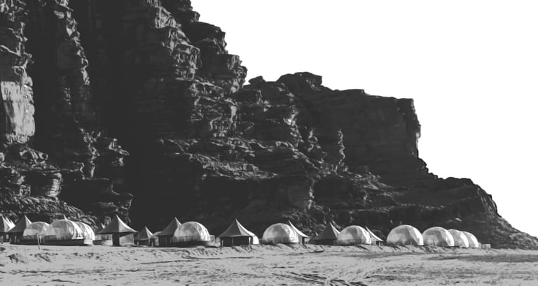 Monochrome landscape photograph showing a line of dome tents and angular shelters deployed along the base of a massive, craggy rock cliff.